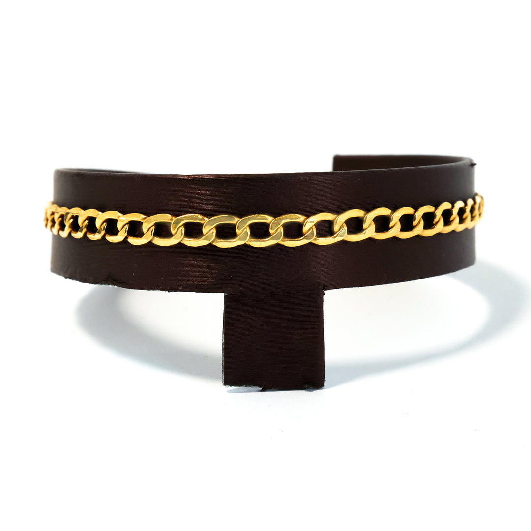 Black leather cuff with gold chain detail on a white background