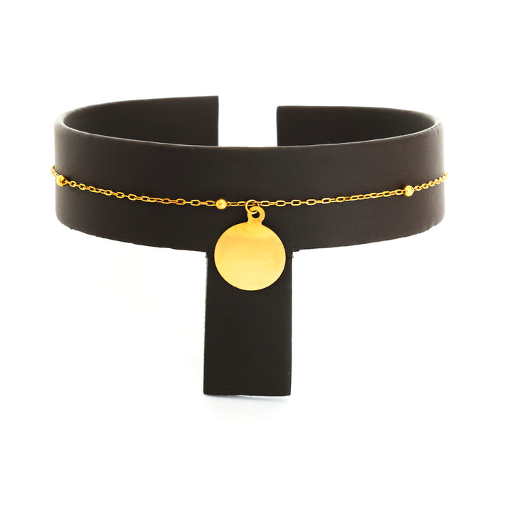 Black choker necklace with gold chain and pendant on a white background