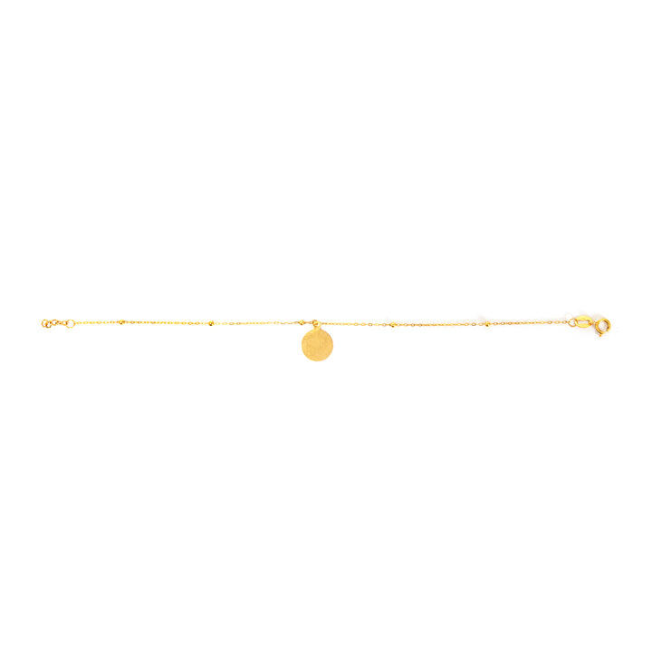 Gold anklet with a round pendant on a white background