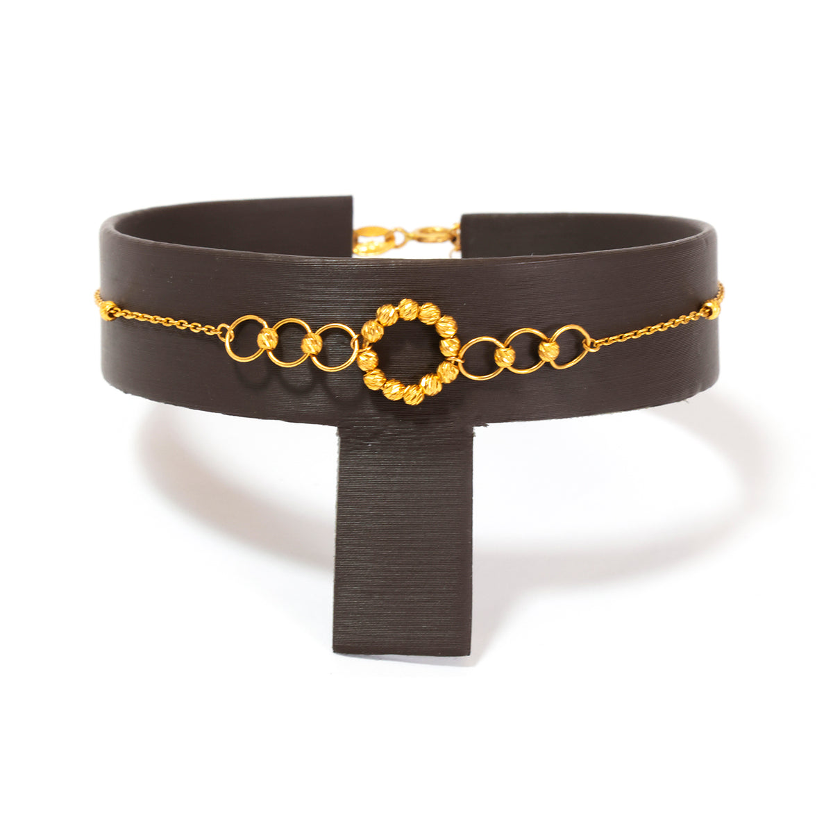 Black choker with gold chain and circular design on a white background