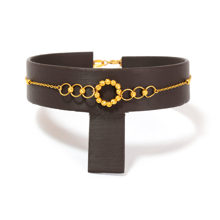 Black choker with gold chain and circular design on a white background