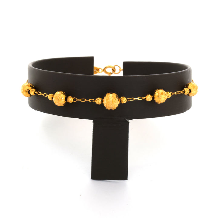 Black choker with gold chain and spherical elements on a white background