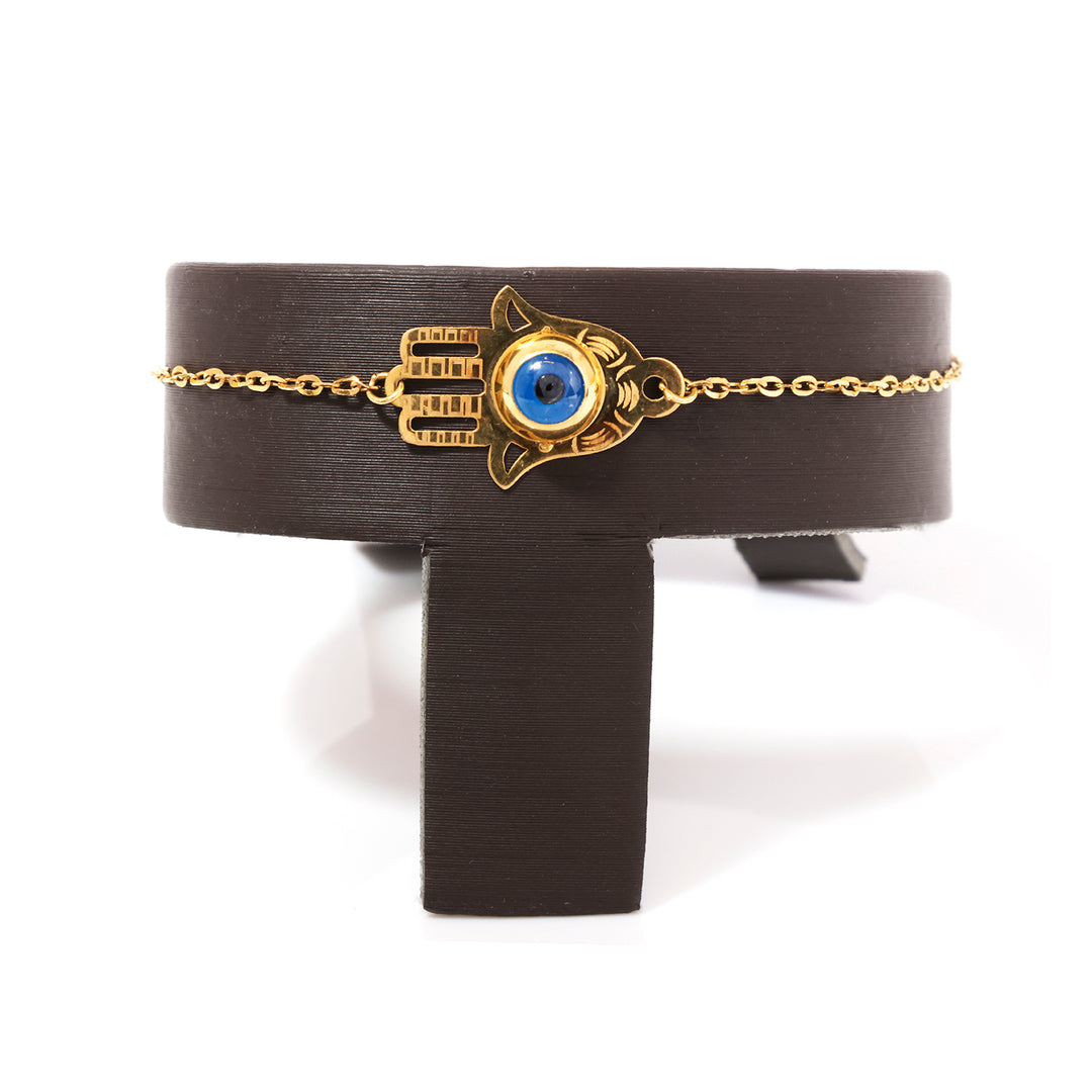 Bracelet with gold chain and blue eye design on a black stand