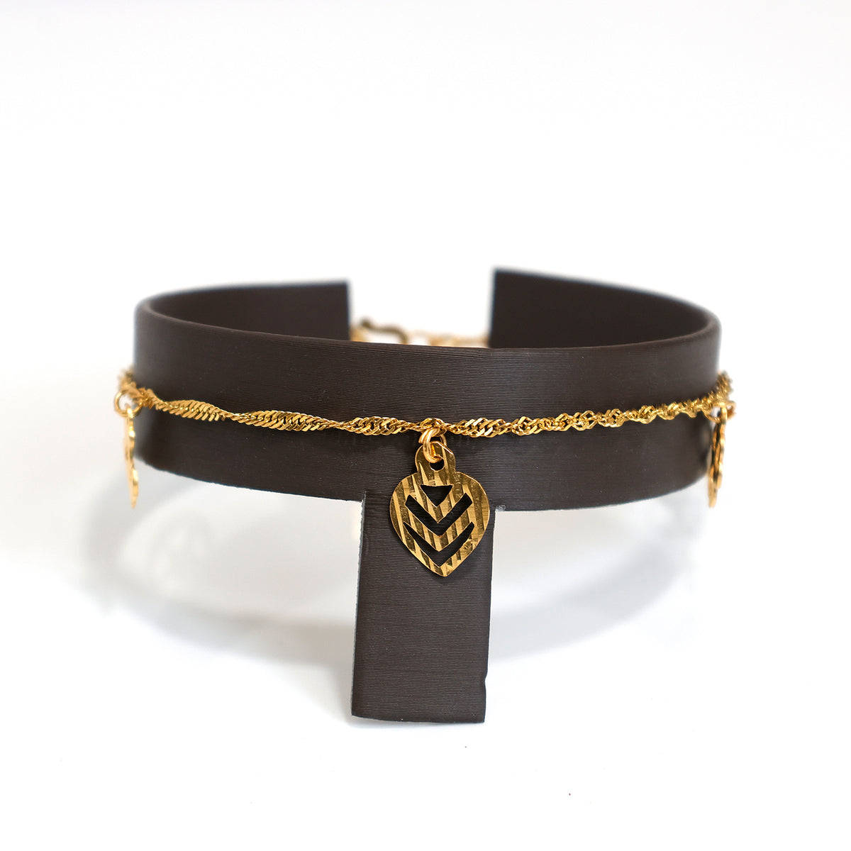 Black leather choker with gold chain and chevron pendant on a white background