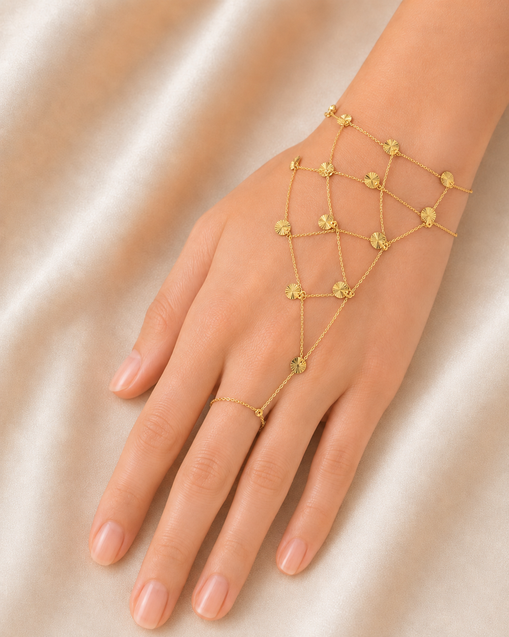 Gold hand chain on a hand against a beige background
