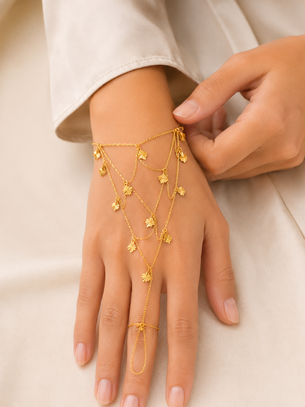 Gold hand chain on a hand against a neutral background