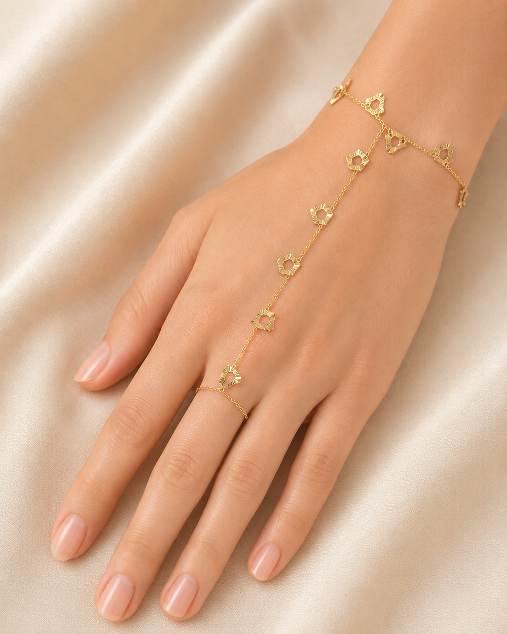 Gold bracelet and ring set on a hand against a beige background