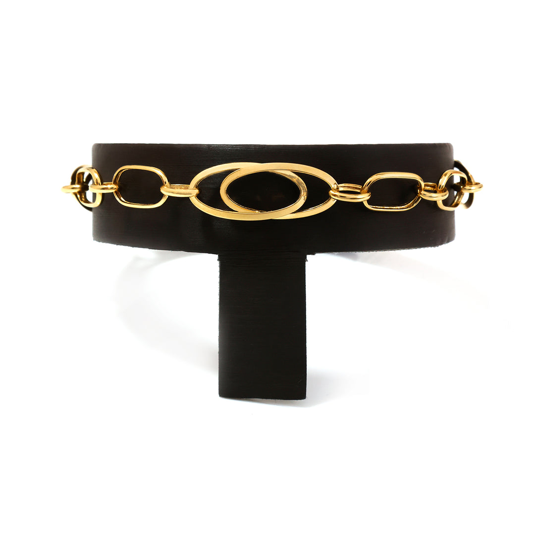 A black leather belt with a prominent gold-tone chain link design across the front, displayed on a black stand against a white background.