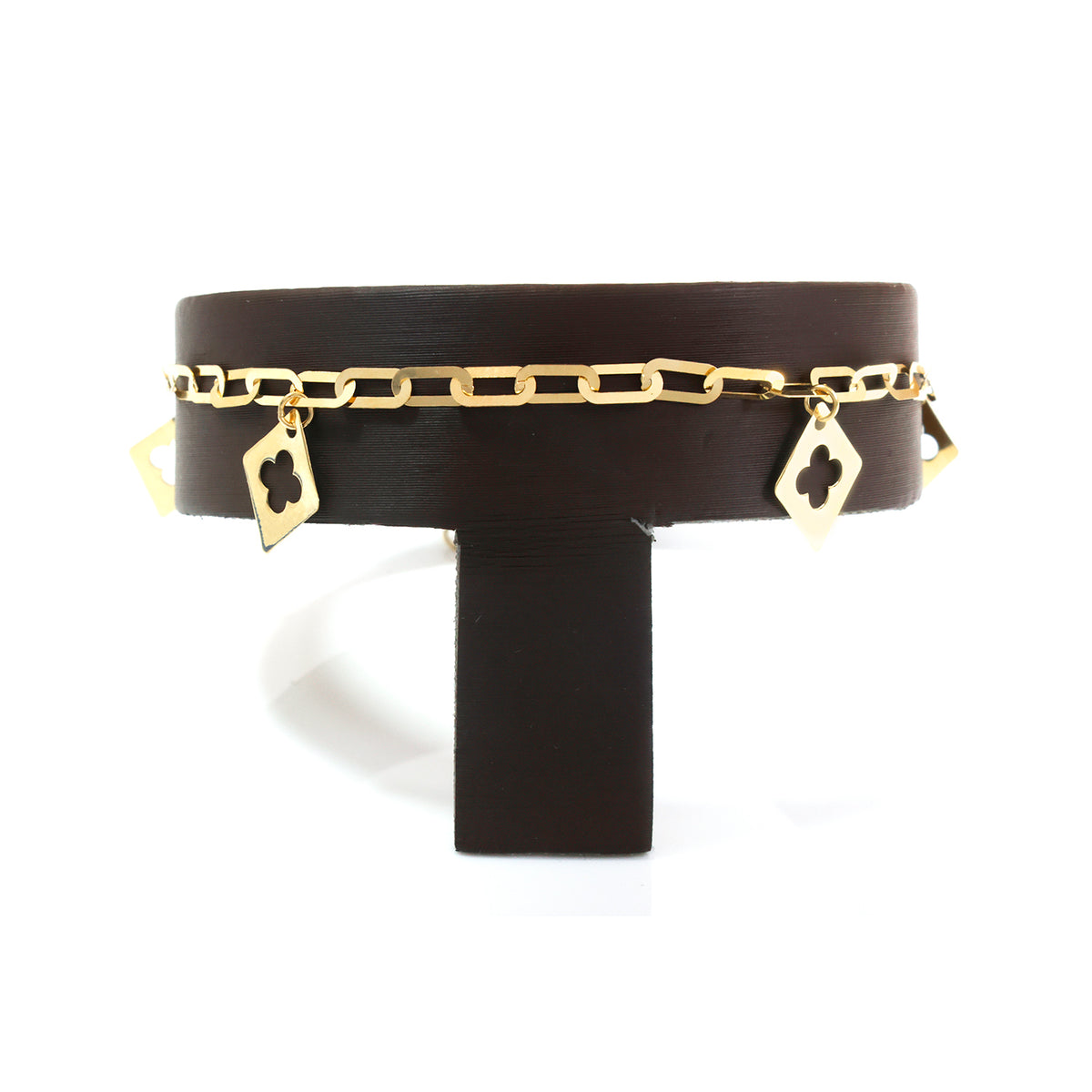 A gold chain bracelet with interlocking links and dangling clover-shaped charms, displayed on a black T-stand against a white background.