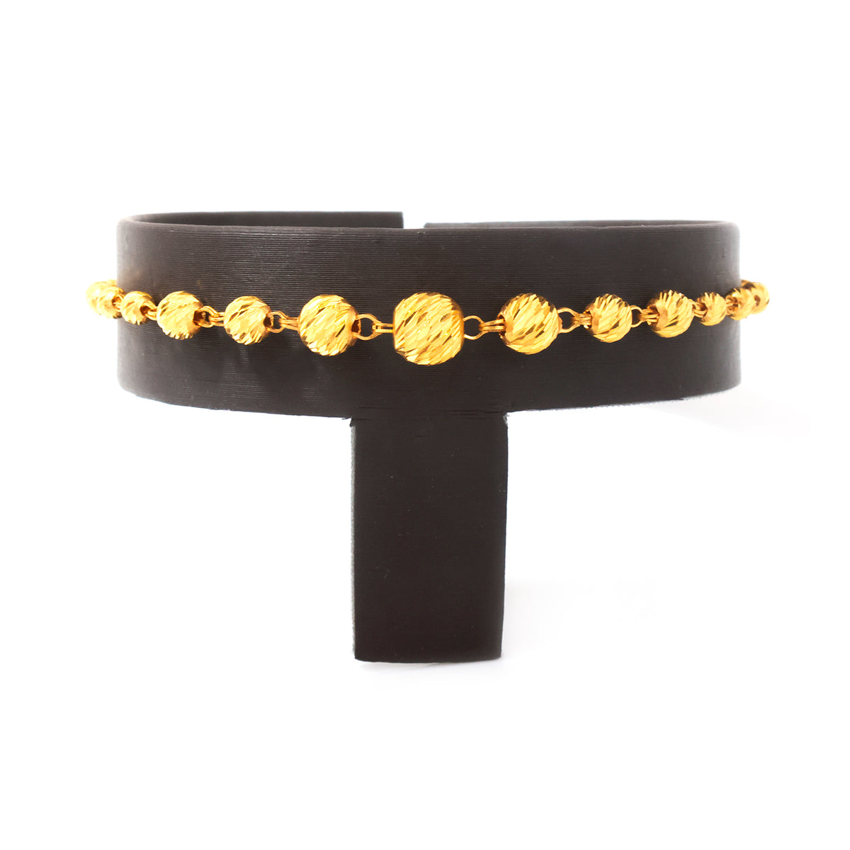 A gold chain bracelet with textured, ribbed oval links, displayed on a black display stand against a white background.