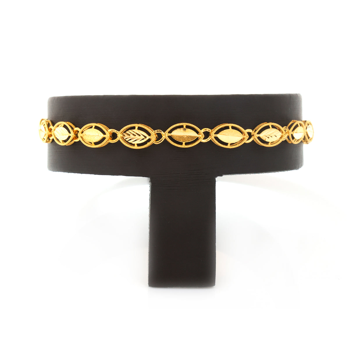 A gold chain bracelet with repeating oval and leaf-like links, displayed on a black T-shaped jewelry stand against a white background.