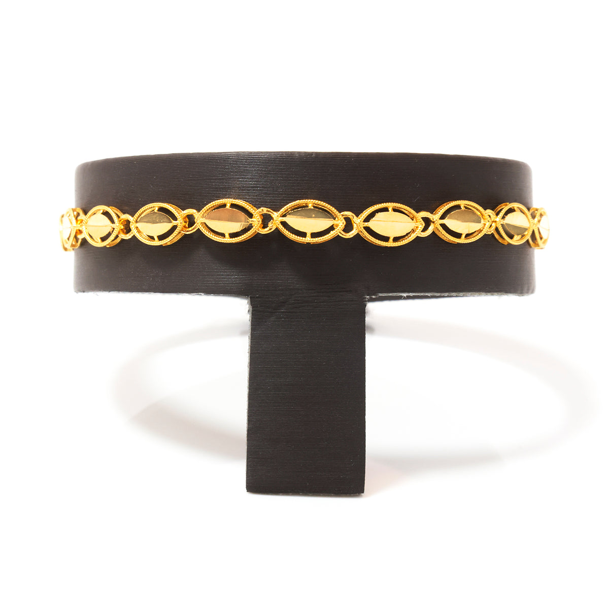 A gold chain bracelet with elongated oval links, displayed on a black stand against a white background.