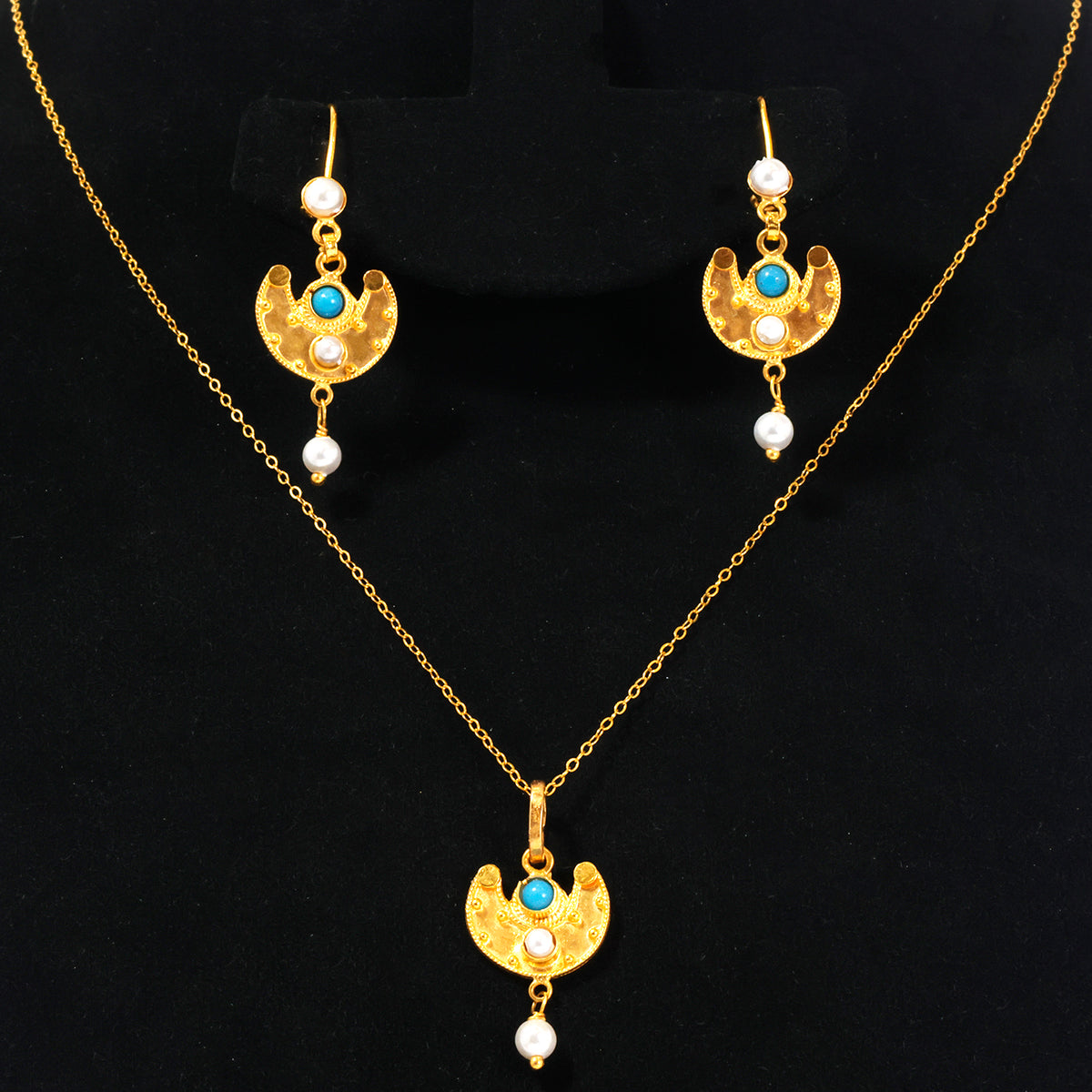 Gold-tone jewelry set featuring a necklace and matching earrings with crescent moon pendants, turquoise blue stones, and small white pearl drops, displayed on a black background.