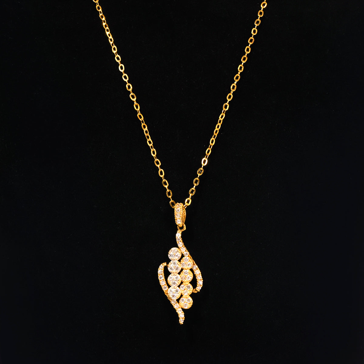 A gold chain necklace with a gold pendant adorned with small clear stones, displayed against a solid black background.