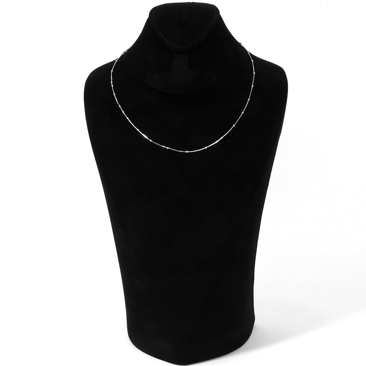 A delicate silver beaded necklace displayed on a black velvet jewelry bust against a white background.
