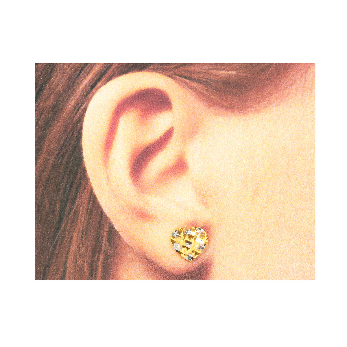 Close-up of an ear wearing a gold heart-shaped earring with a white background