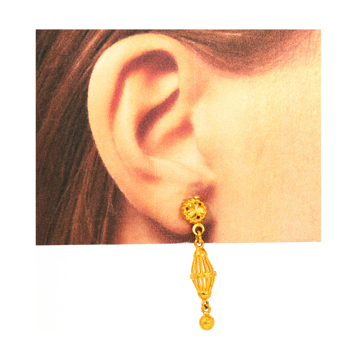 Gold earring worn on an ear with a plain background