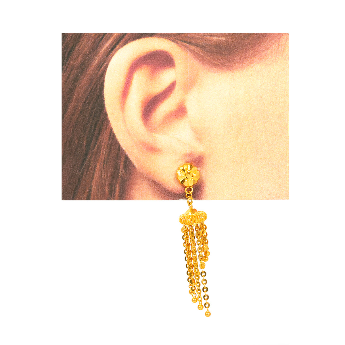 Gold earring with dangling beads worn on an ear against a neutral background