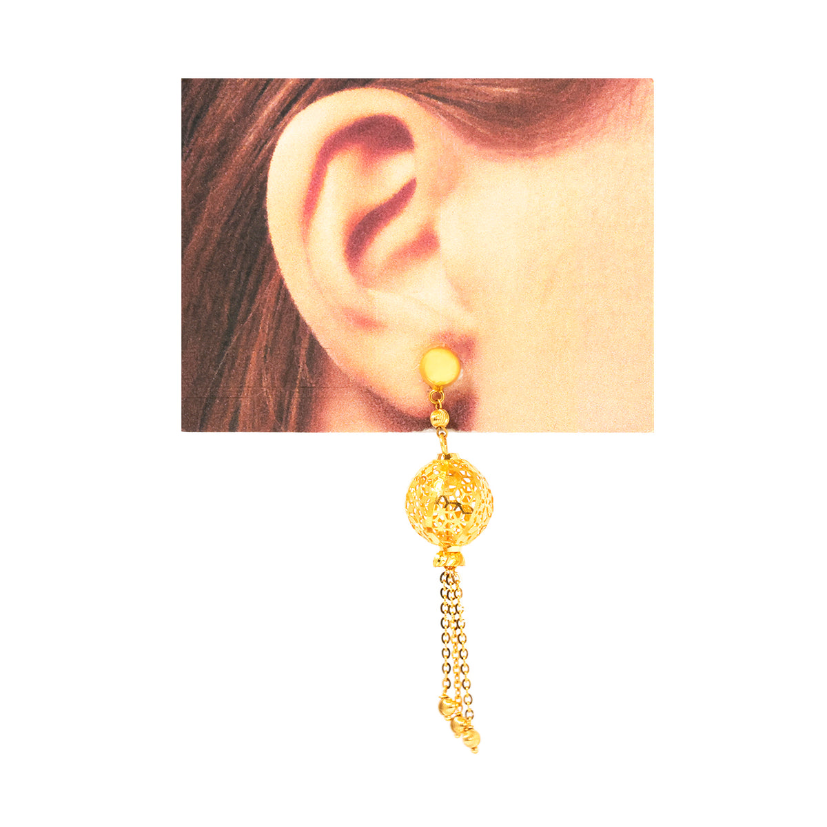 Gold earring worn on an ear with a plain background