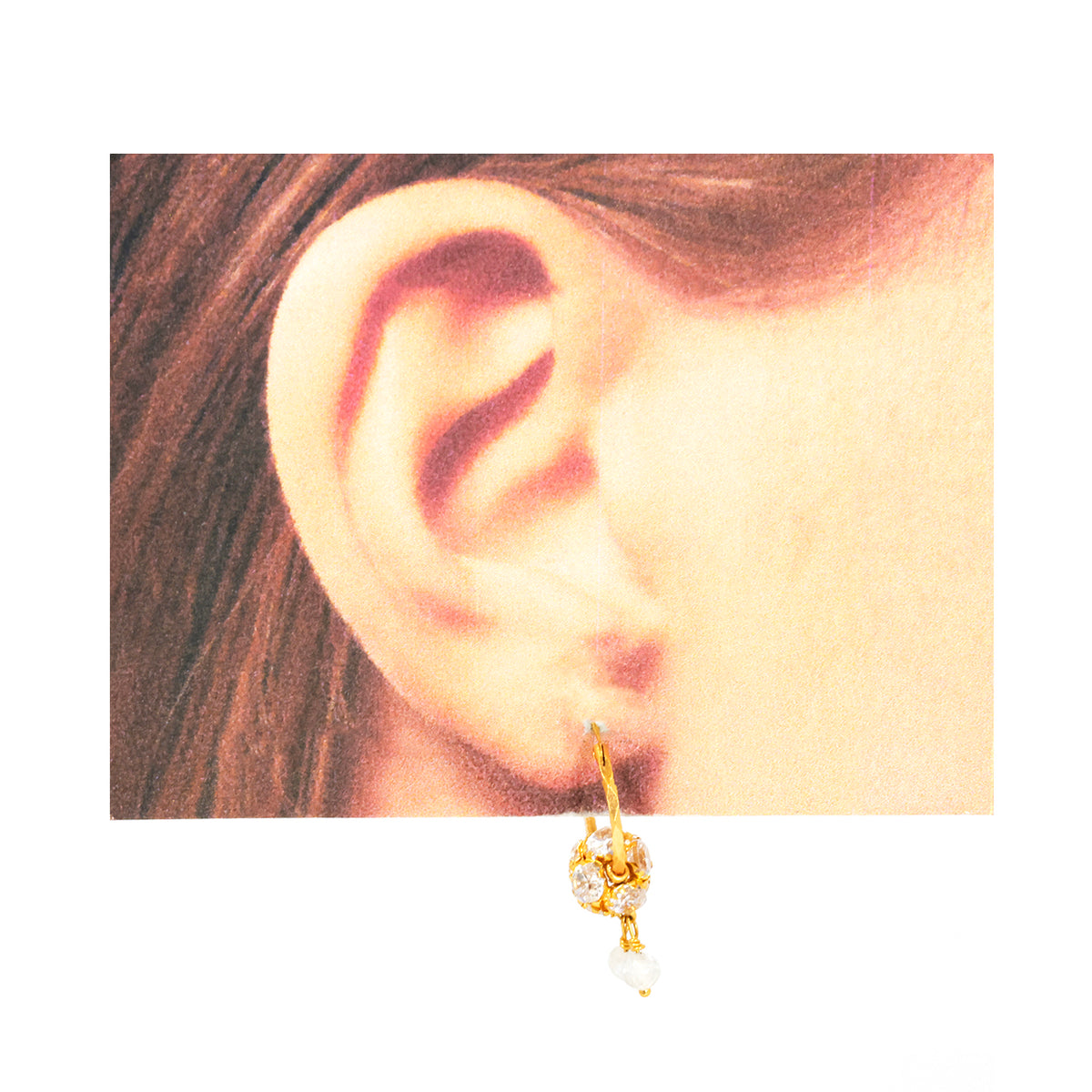 Gold earring worn by a person with brown hair.