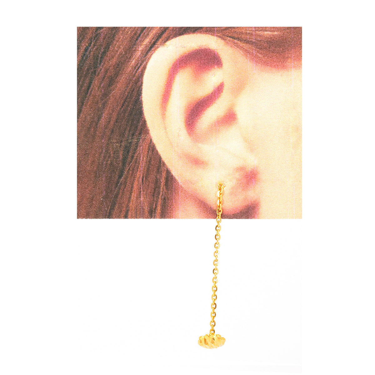 Gold earring with chain hanging in front of an ear