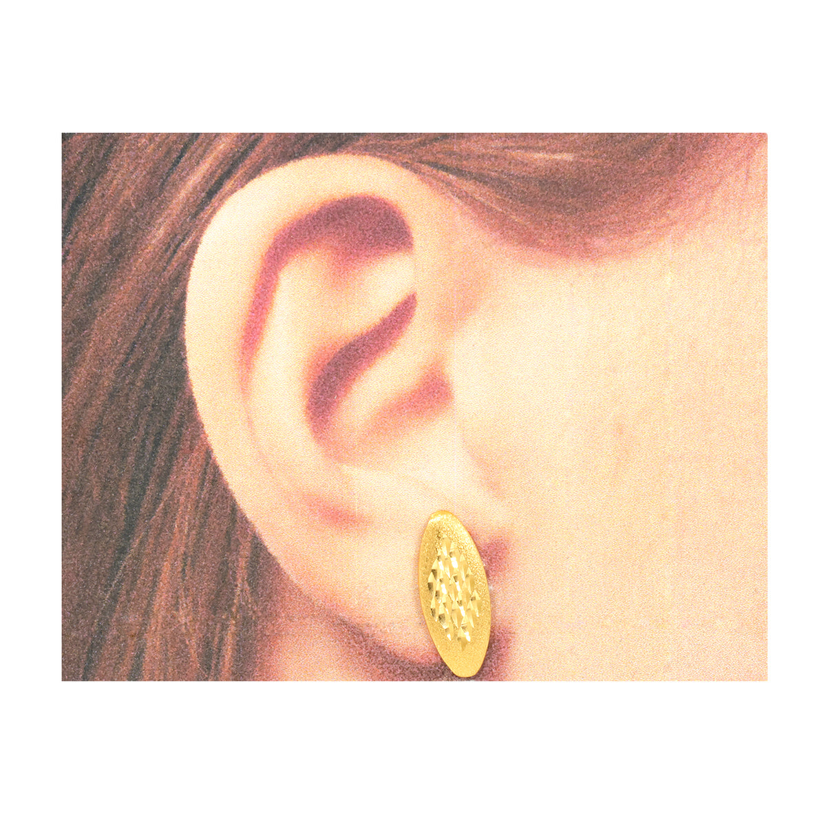 Gold earring worn on an ear with a plain background