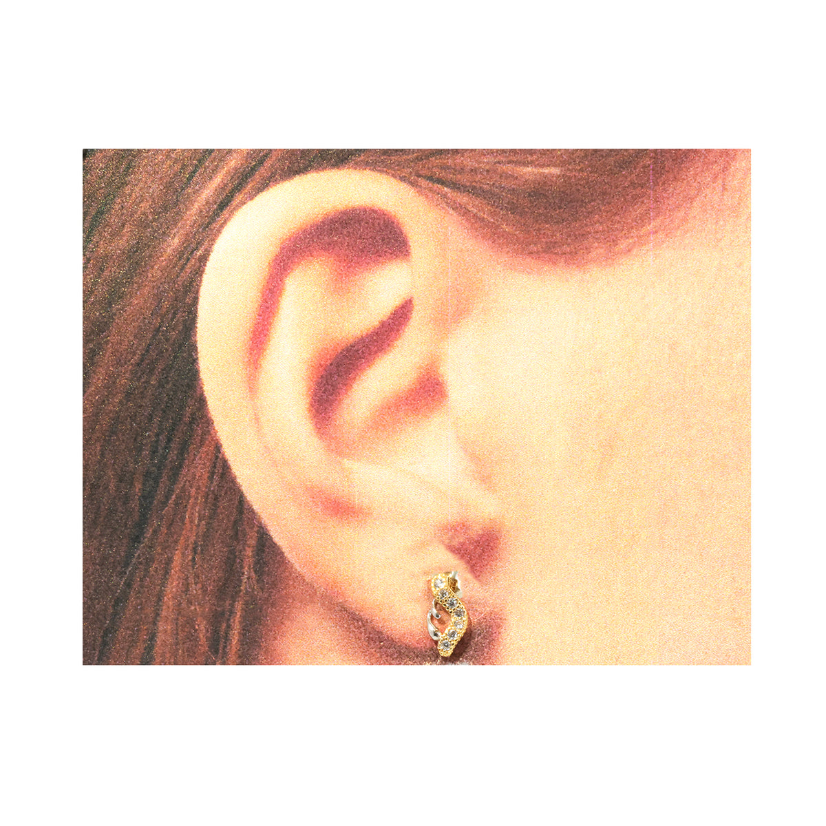Close-up of an ear wearing a gold hoop earring with hair partially visible.