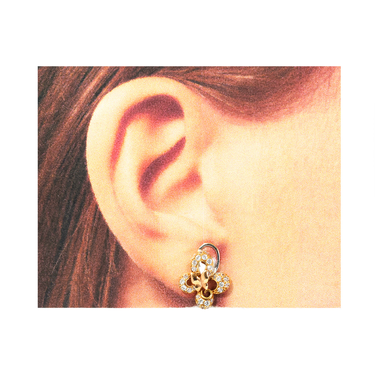 Close-up of an ear wearing a gold earring with a floral design.