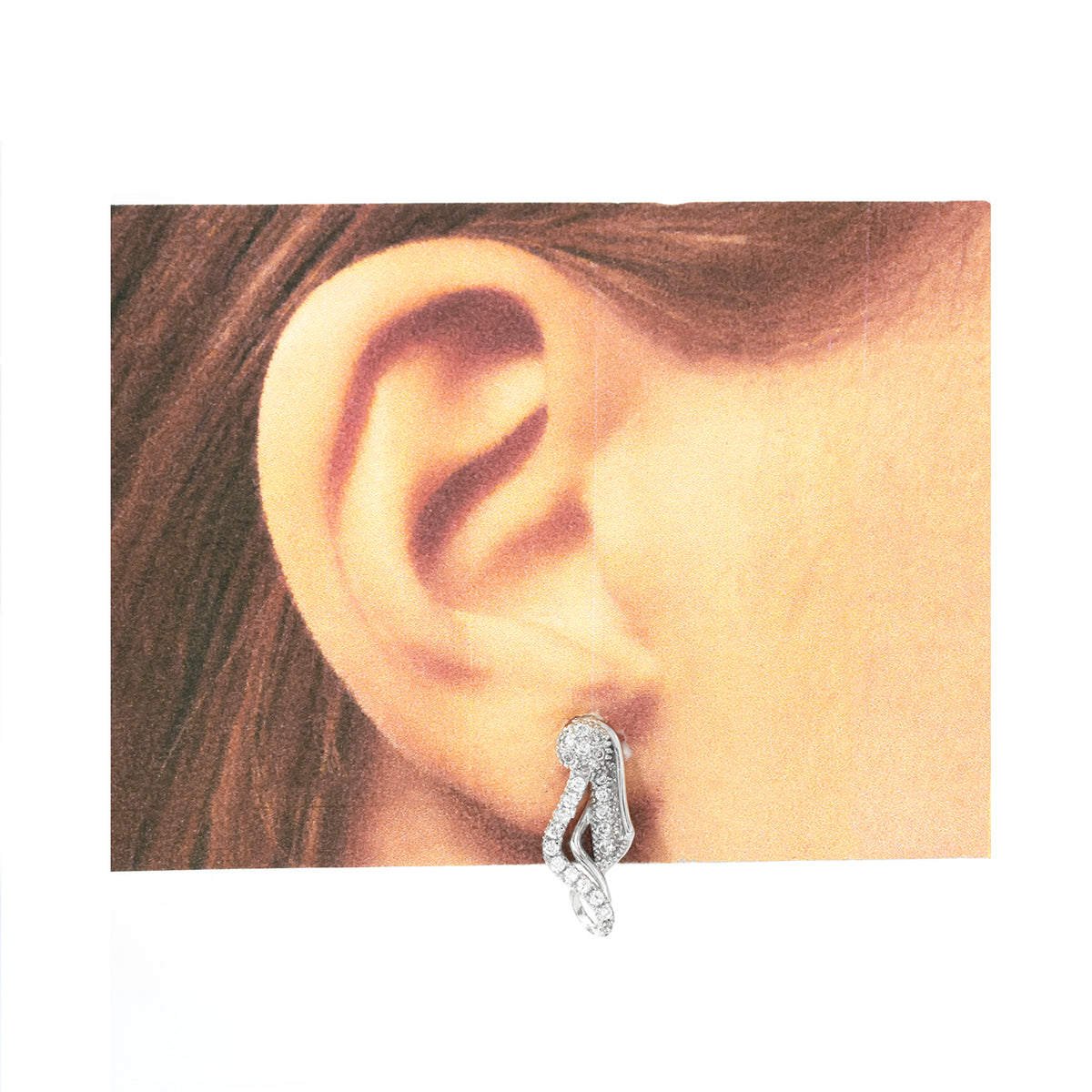 Silver earring worn on a model's ear with a plain background