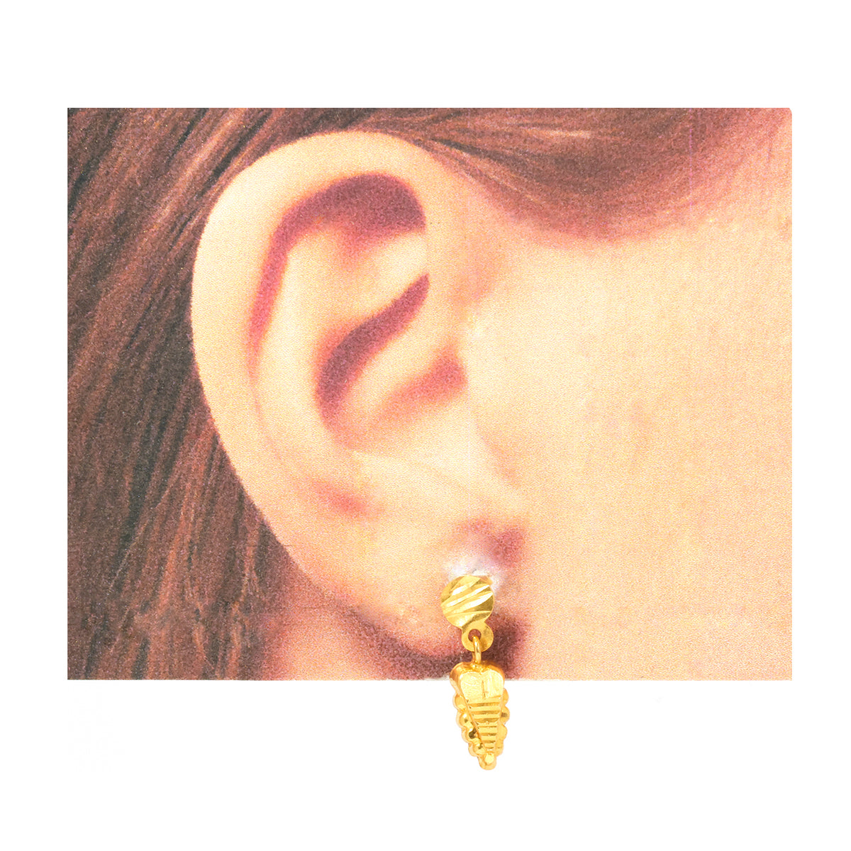 Gold earring worn on an ear with a plain background
