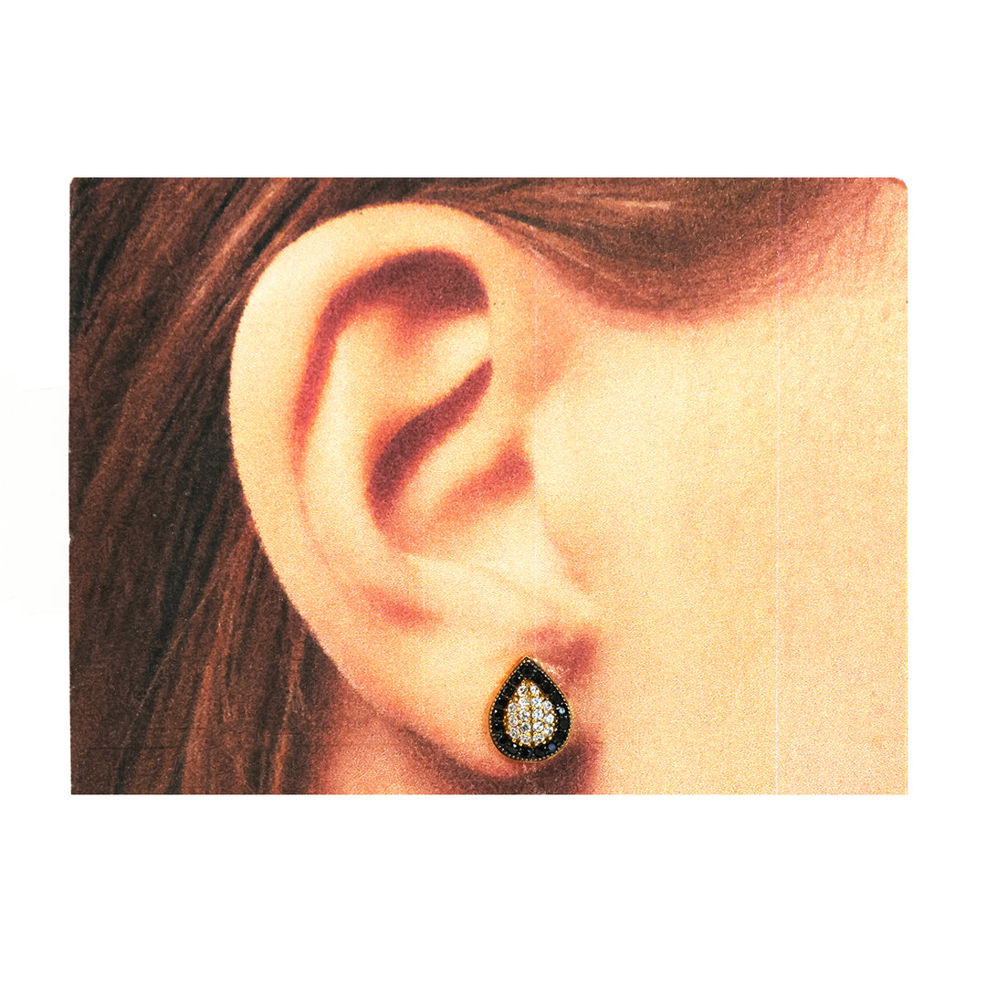 Close-up of an ear wearing a teardrop-shaped earring with black and gold details.