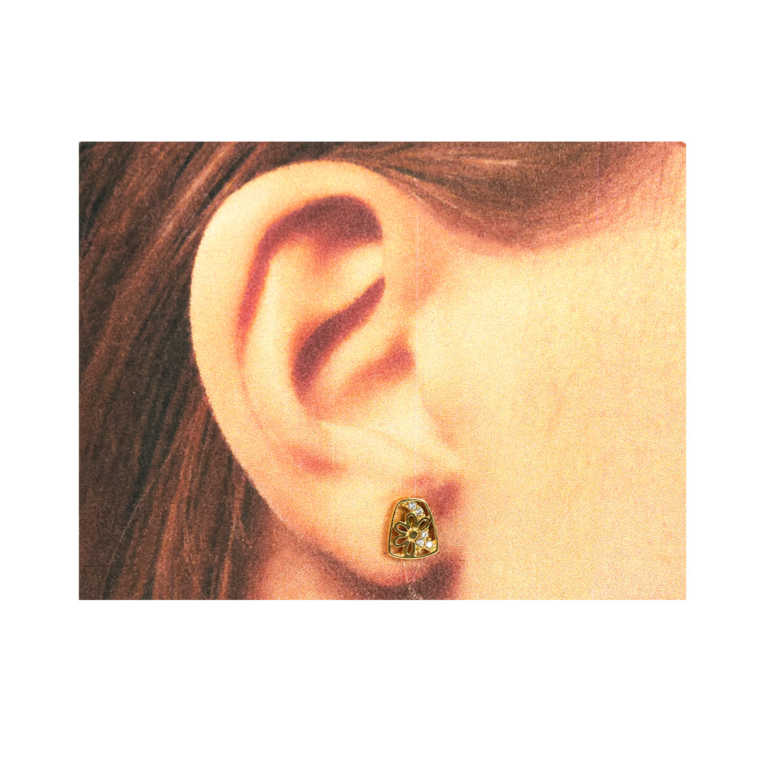 Close-up of an ear wearing a gold earring with a green gemstone.