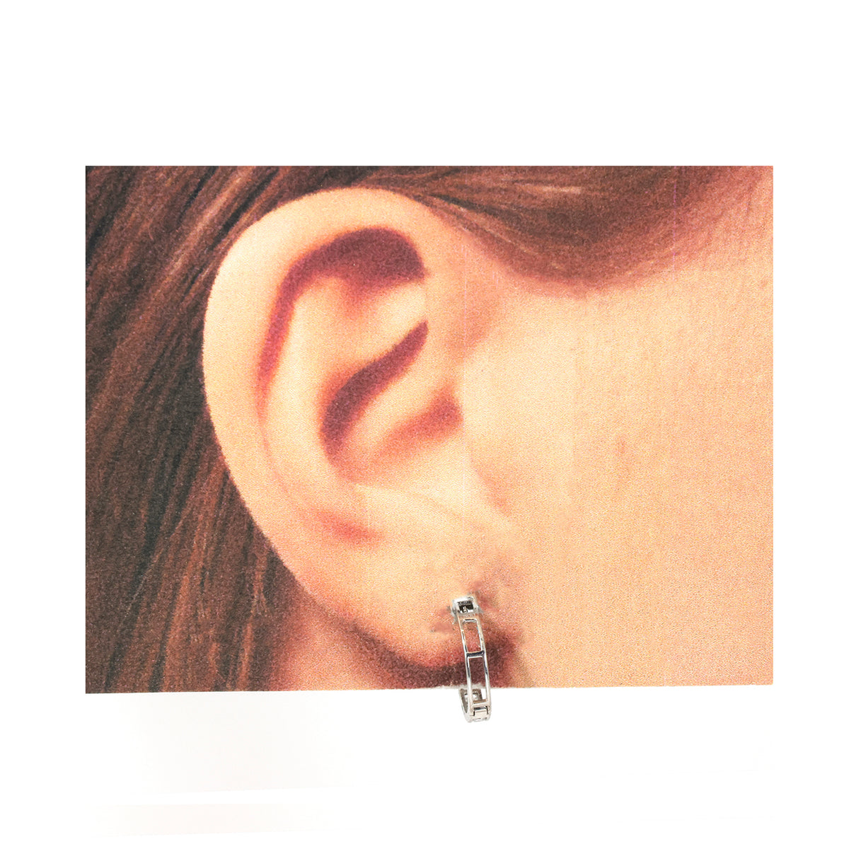 Close-up of an ear wearing a silver hoop earring on a plain background