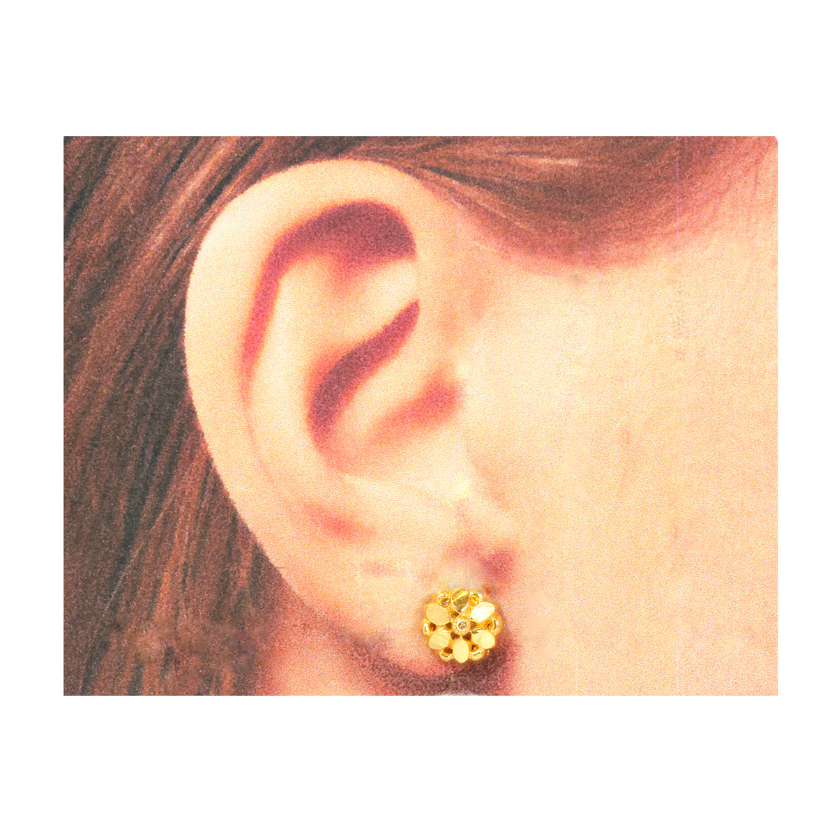 Gold earring worn on an ear with a plain background