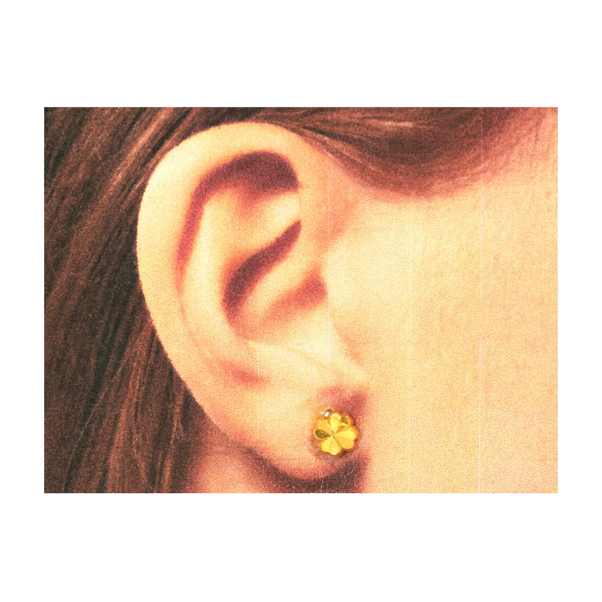 Close-up of an ear wearing a yellow flower-shaped earring on a white background