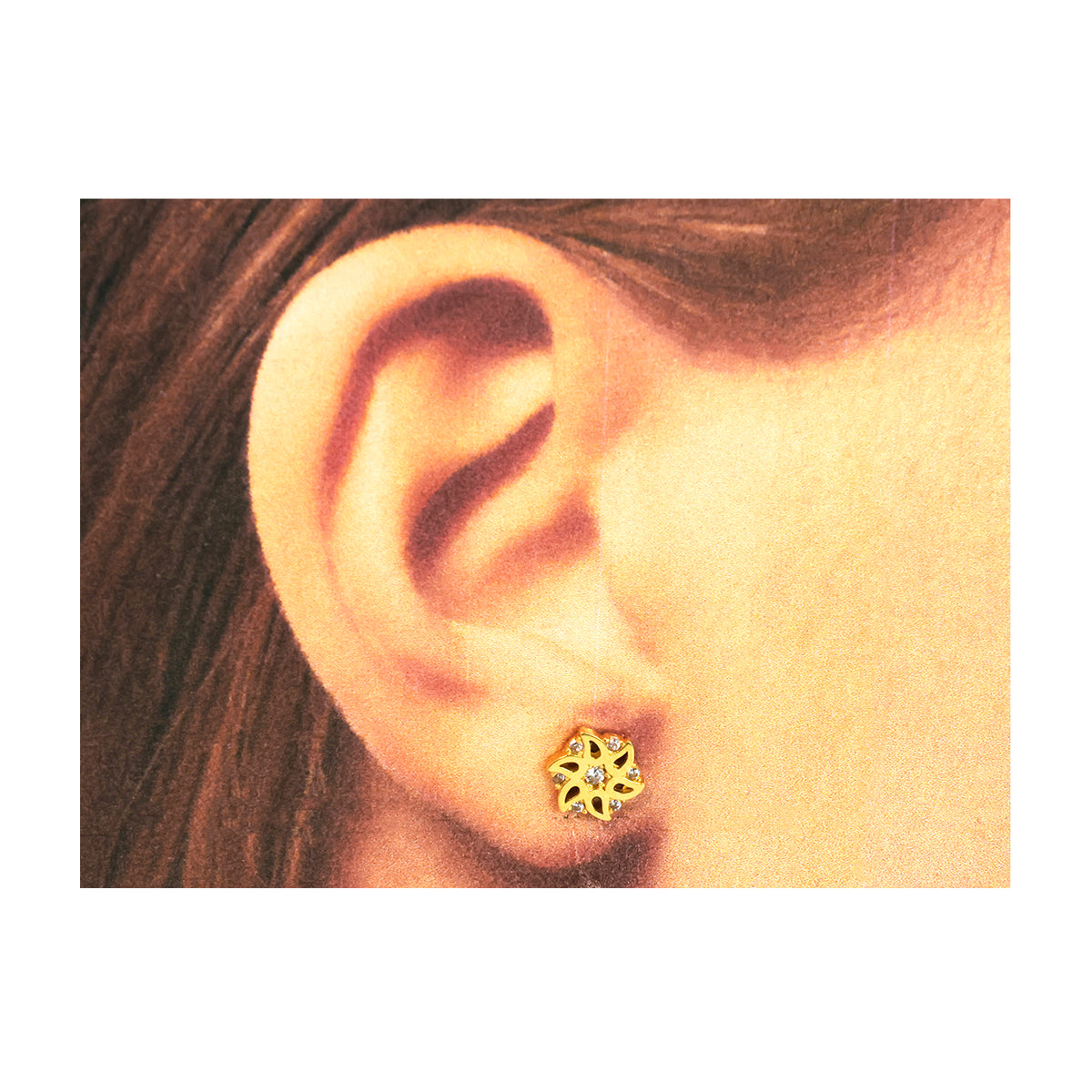 Close-up of an ear wearing a gold earring with a floral design.