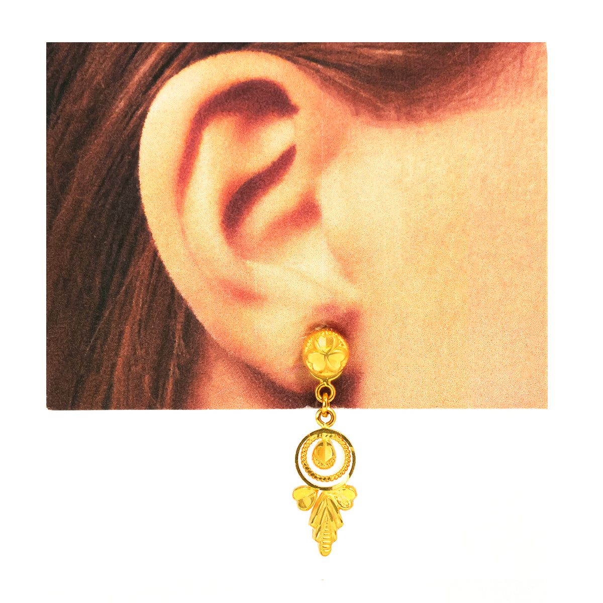 Gold earring worn on an ear with a plain background