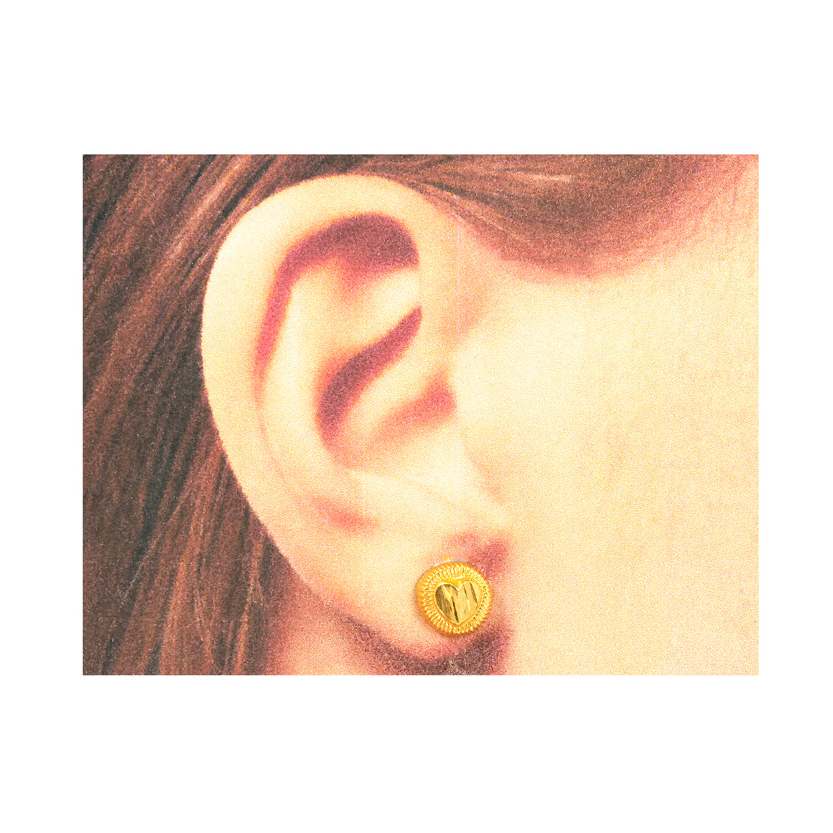 Gold earring worn on an ear with a plain background