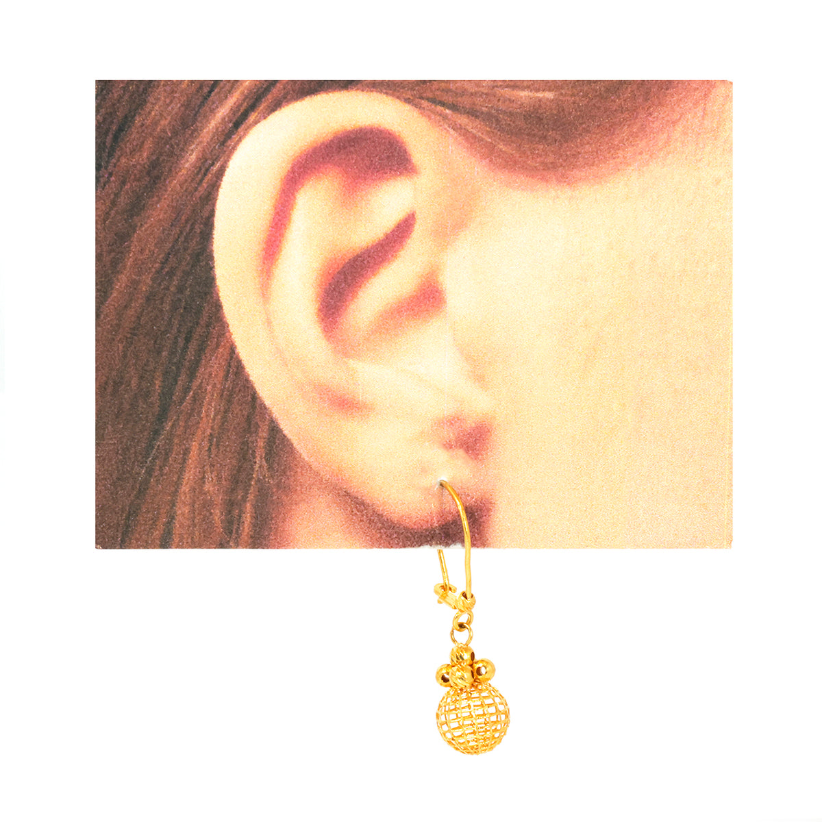 Gold earring worn on an ear with a plain background