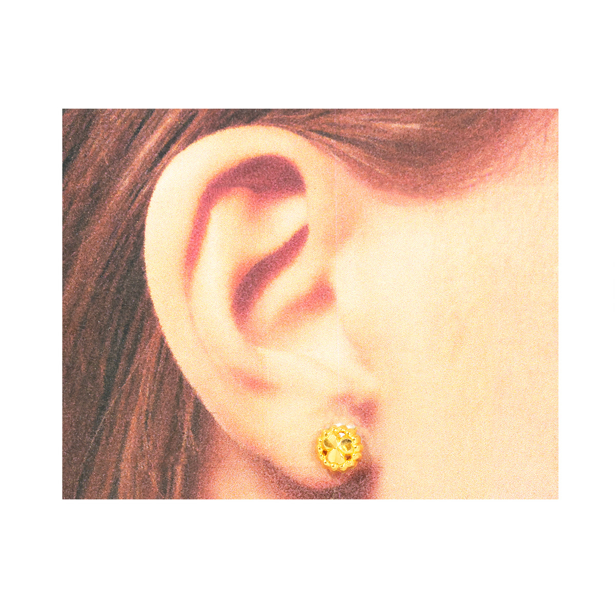 Close-up of an ear wearing a gold earring with a gemstone on a white background