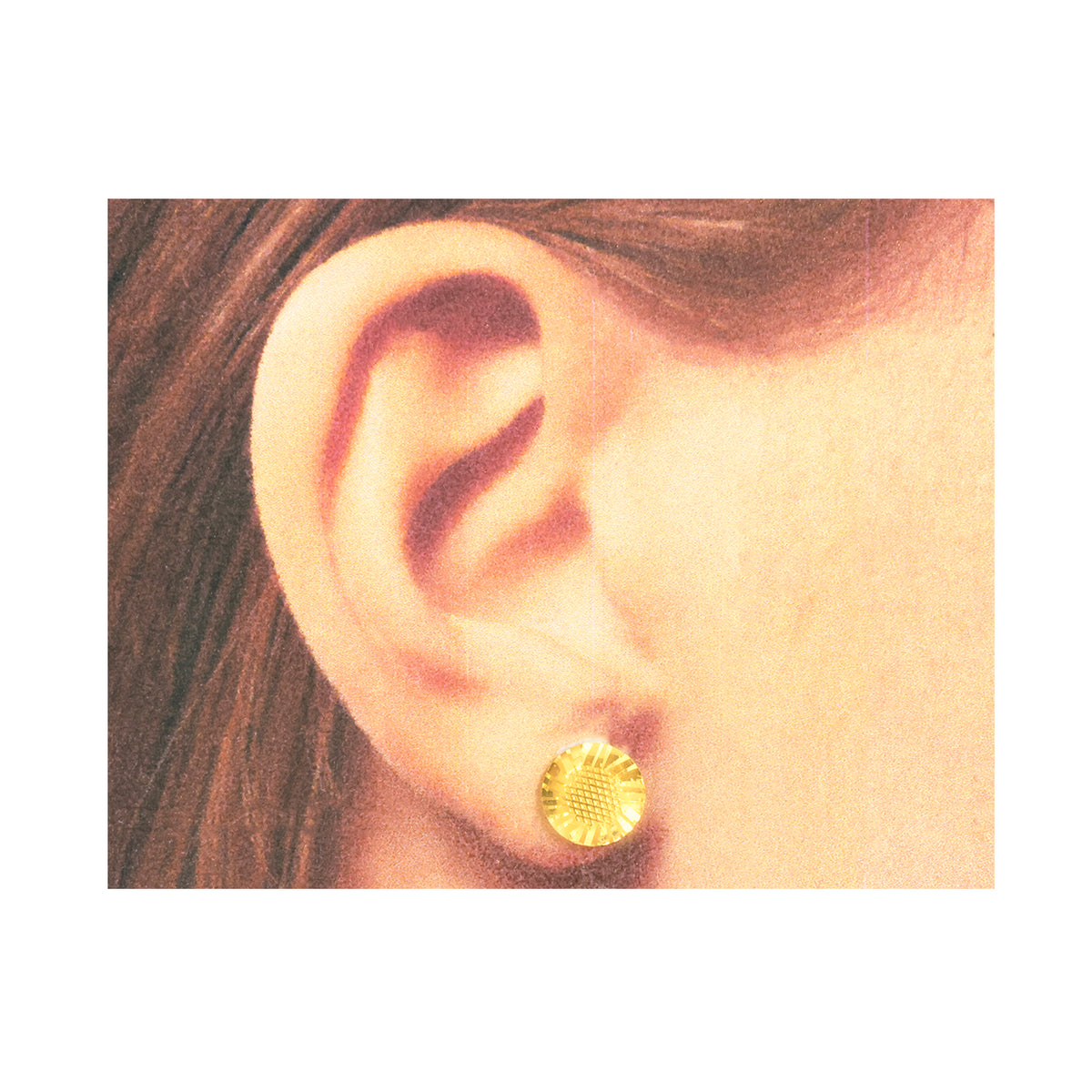 Gold earring worn by a person with brown hair on a white background
