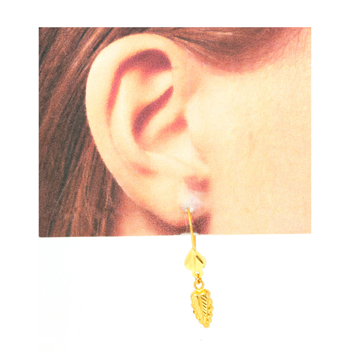 Gold earring with a leaf design worn by a person