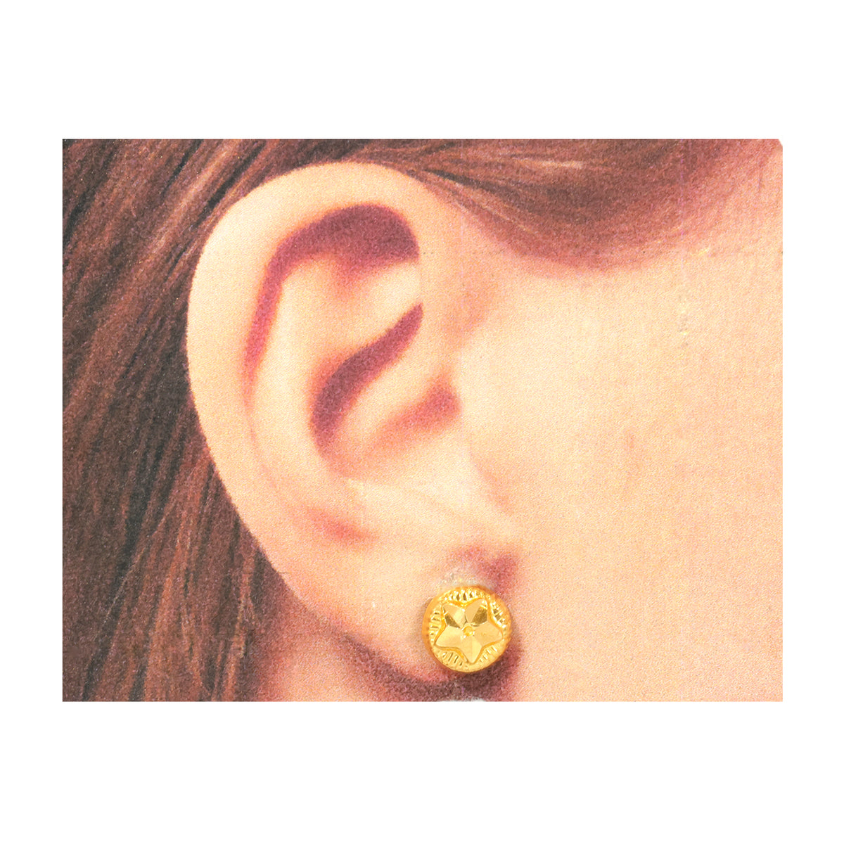 Gold earring worn on an ear with a plain background
