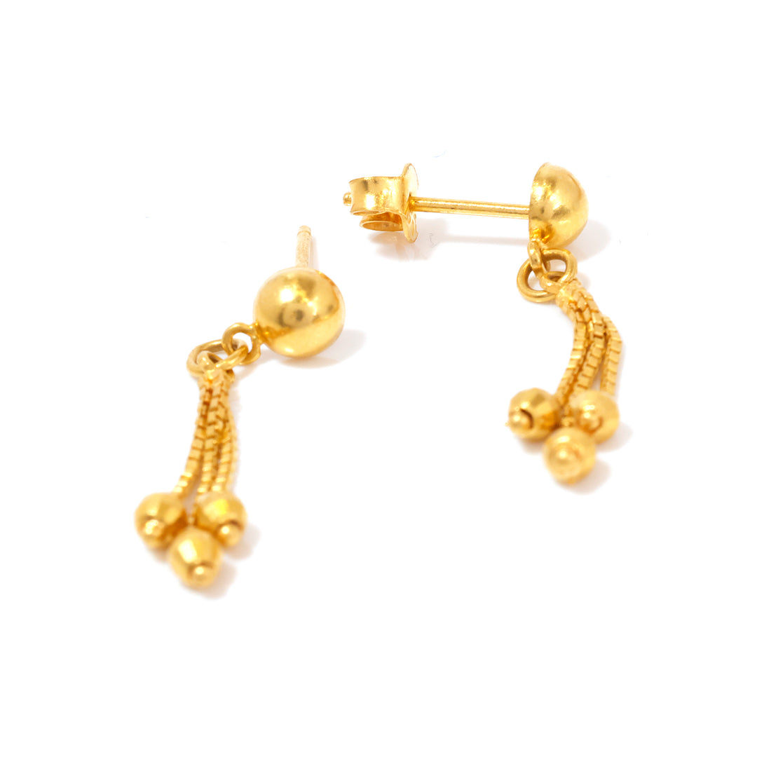 Gold earrings with dangling beads on a white background