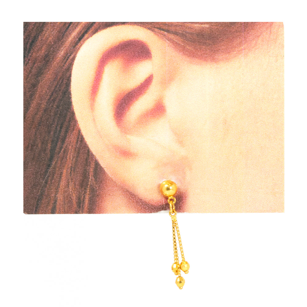 Gold earring worn on an ear with a plain background