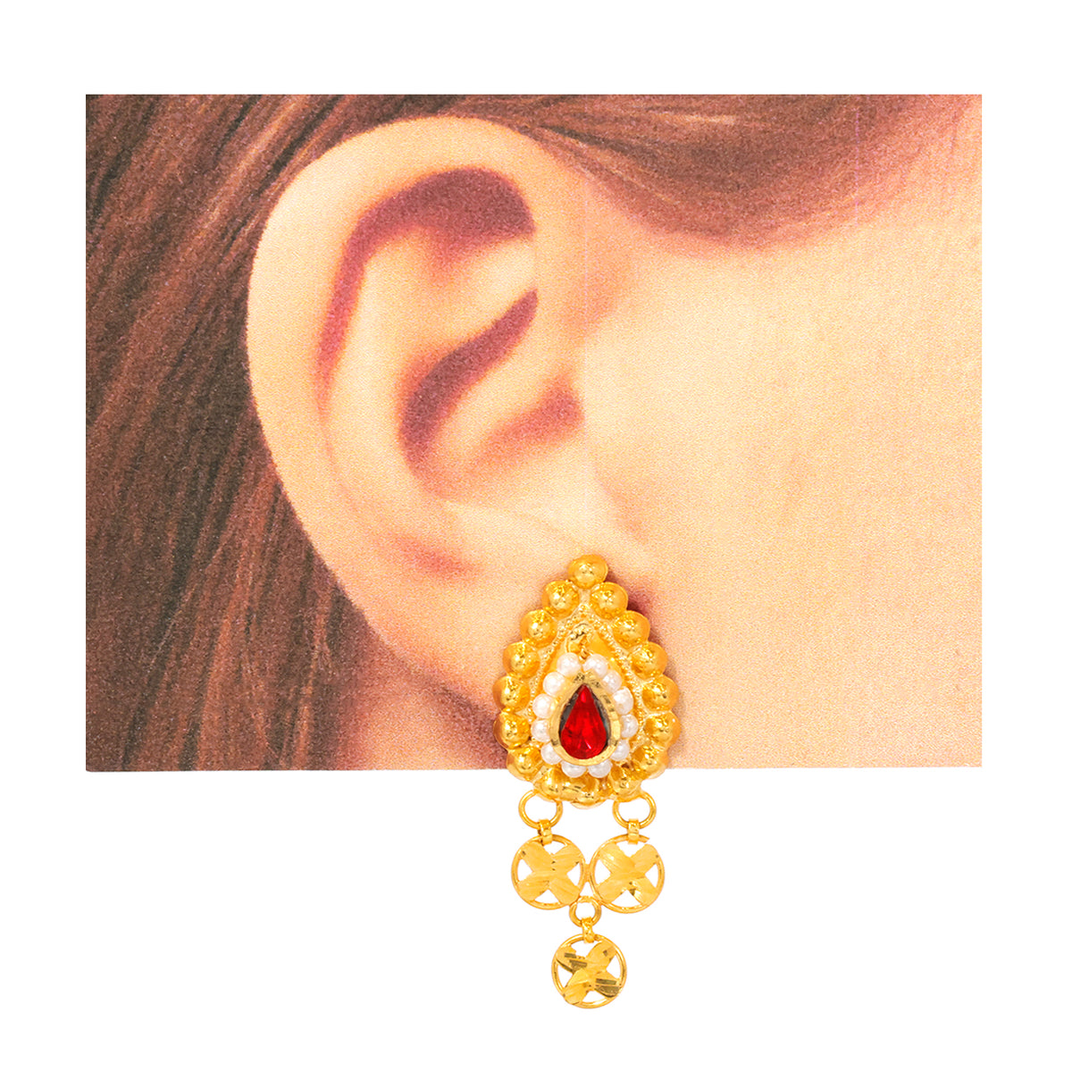 Gold earring with red gemstone worn on an ear