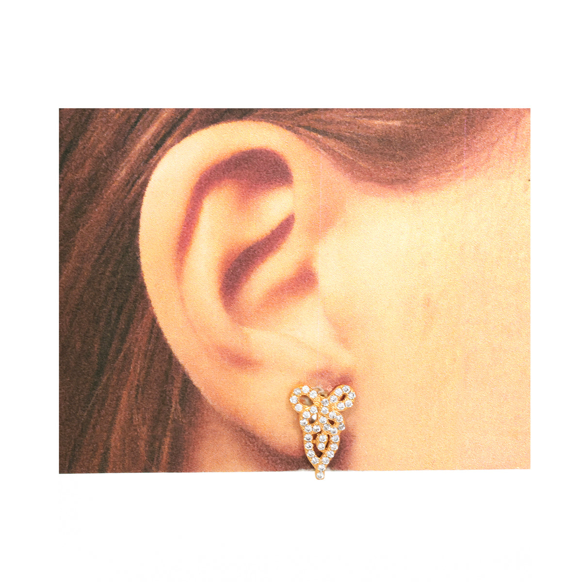 Close-up of an ear wearing a decorative earring on a white background