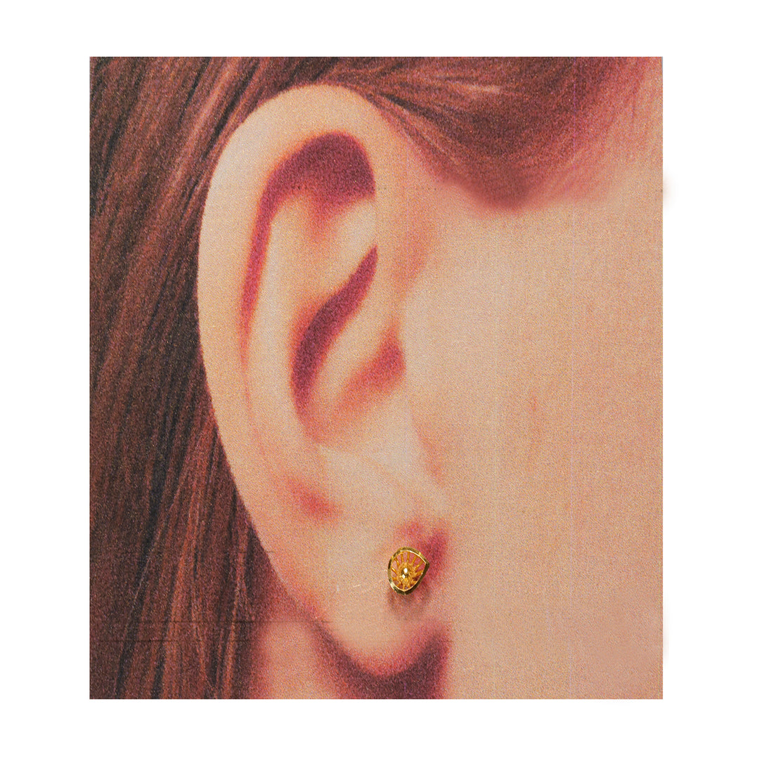 Close-up of an ear wearing a gold earring with a gemstone.