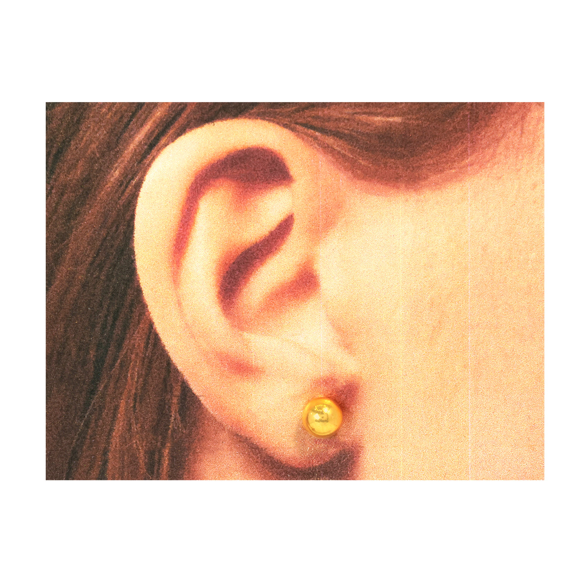 Close-up of an ear wearing a gold earring with a plain background