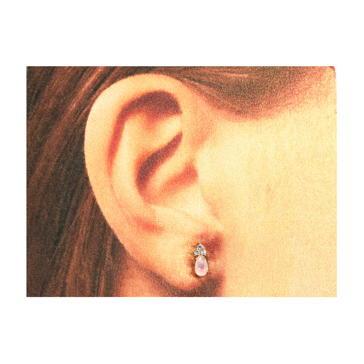 Close-up of an ear wearing a small earring with a clear gemstone.